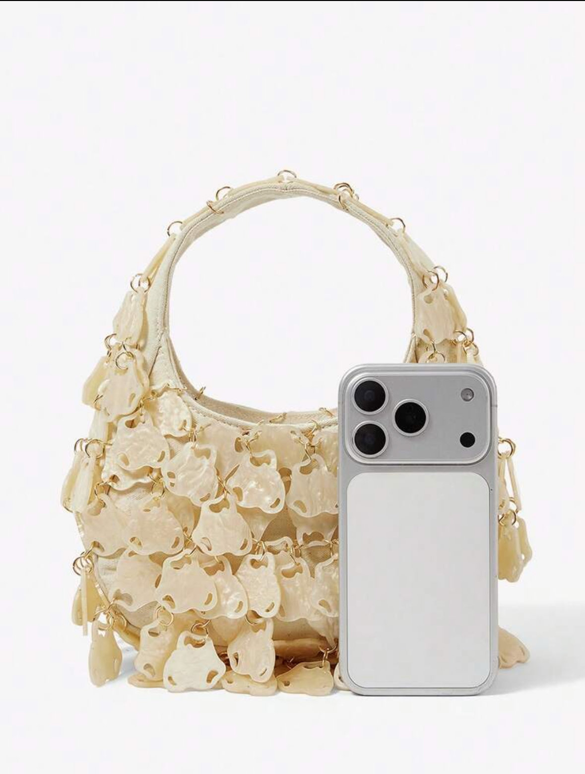 Beige handbag with floral patterns next to a smartphone on a white background