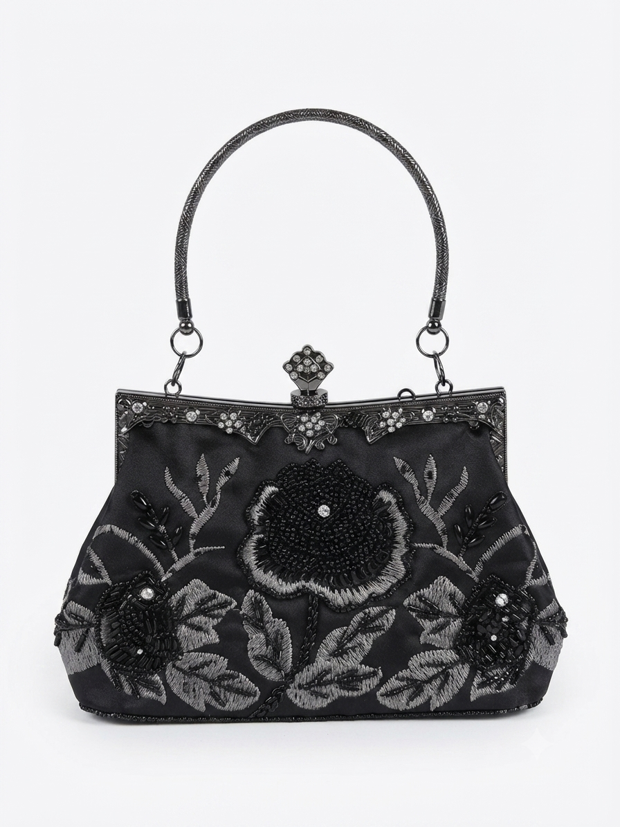 A black structured handbag with a top handle, featuring intricate floral embroidery and beadwork in black and silver on a light gray background.